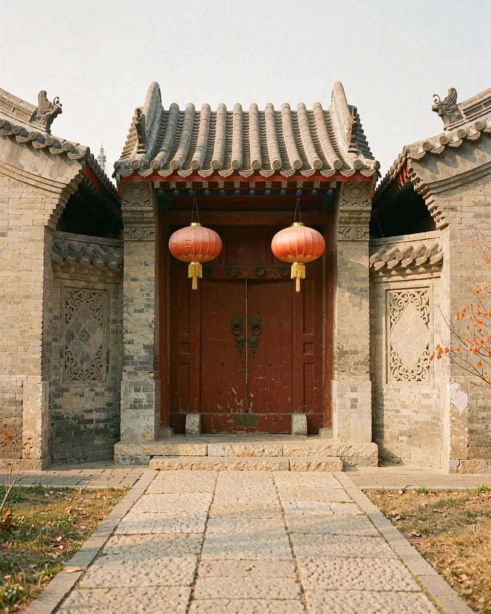 Traditional Chinese courtyard entrance with timber doors, brick walls and two plain red lanterns