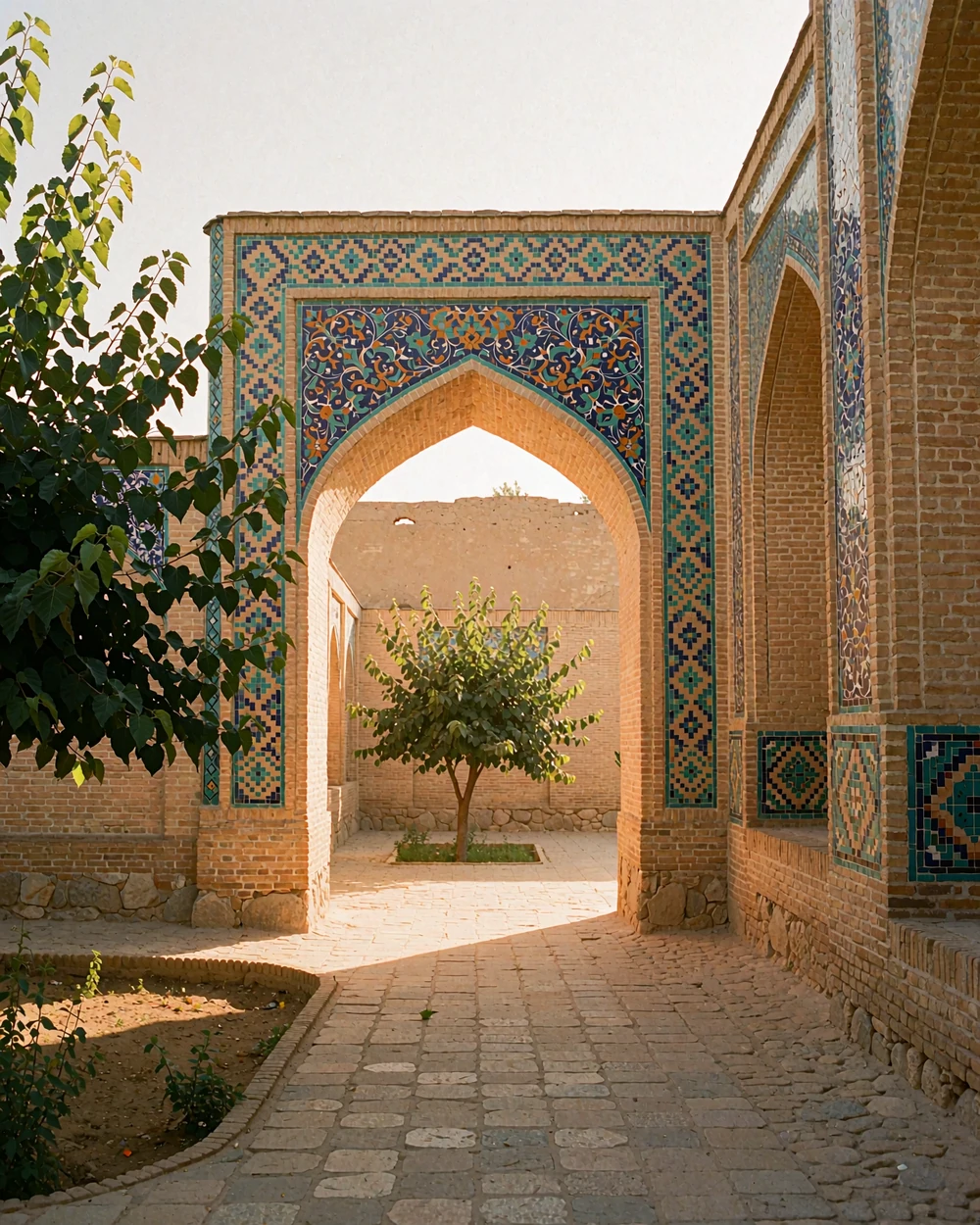 Historic Uzbek courtyard passage with tiled archway and a stone path toward a mulberry tree