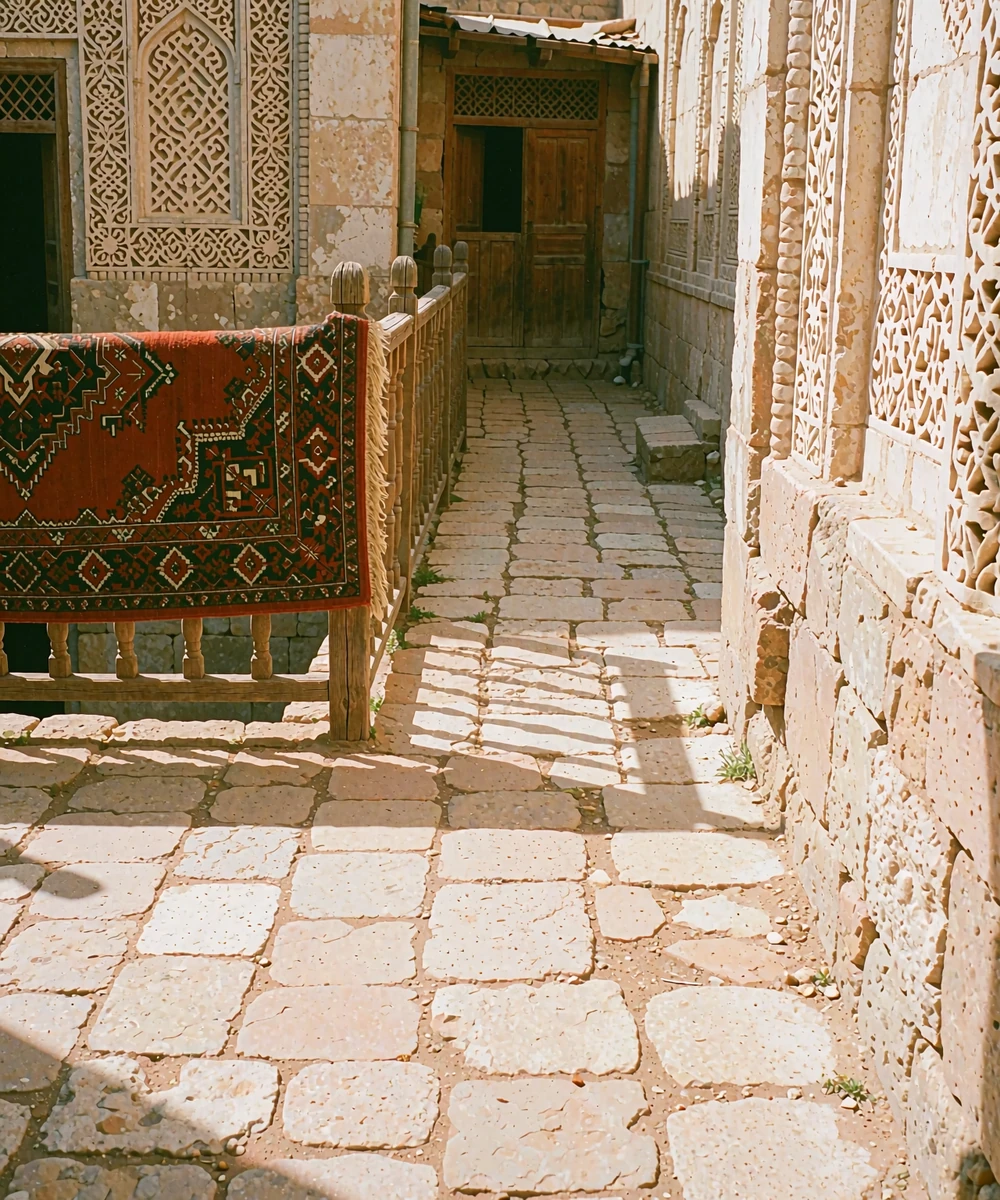 Sunlit Central Asian courtyard with a handwoven carpet, pale stone walls and a shaded wooden doorway